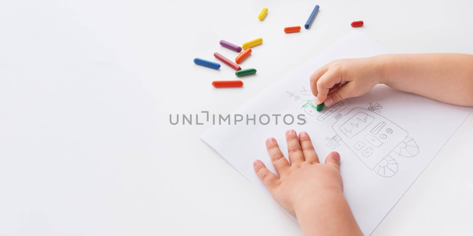 Toddler draws colorful robot. Kid uses wax crayons to paint it. Coloring pages to train fine motor skills on white background with copy space.