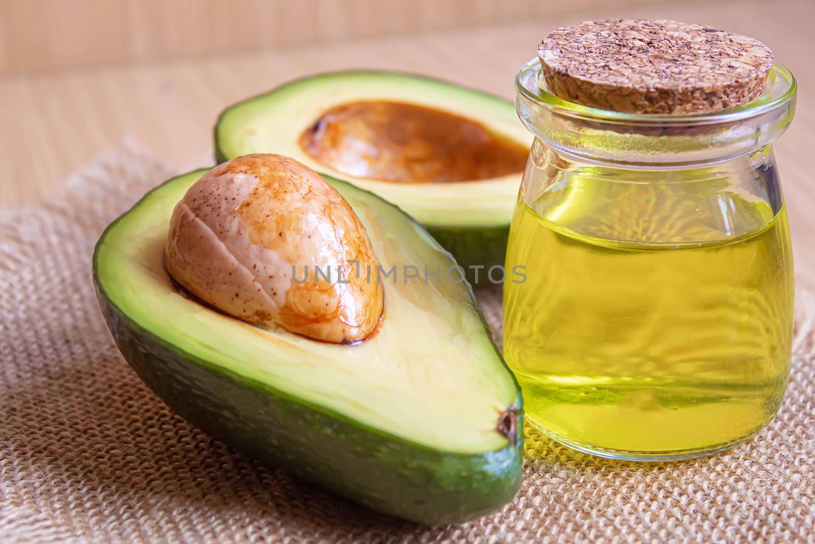 Avocado and avocado oil on wooden background. Selective focus by mila1784