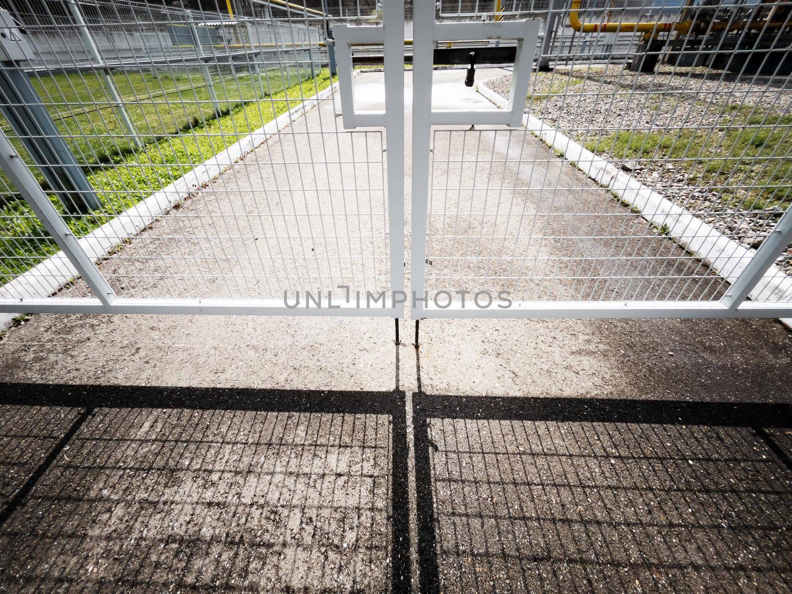 Closed gate made of lattice with a contrasting shadow on the pavement