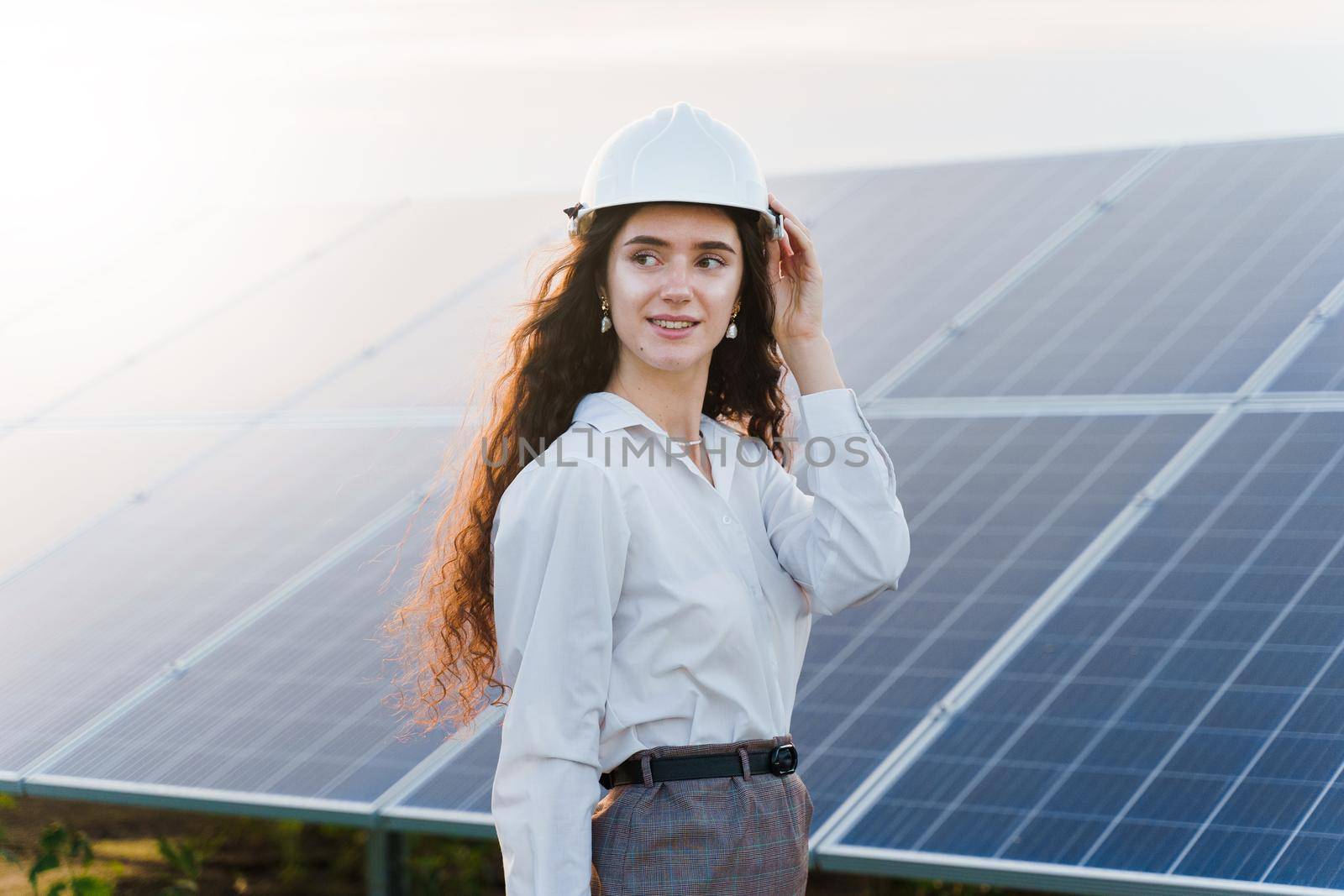 Engineer with solar panels stands in row on the ground at sunset. Green energy. Solar cells power plant business. by Rabizo