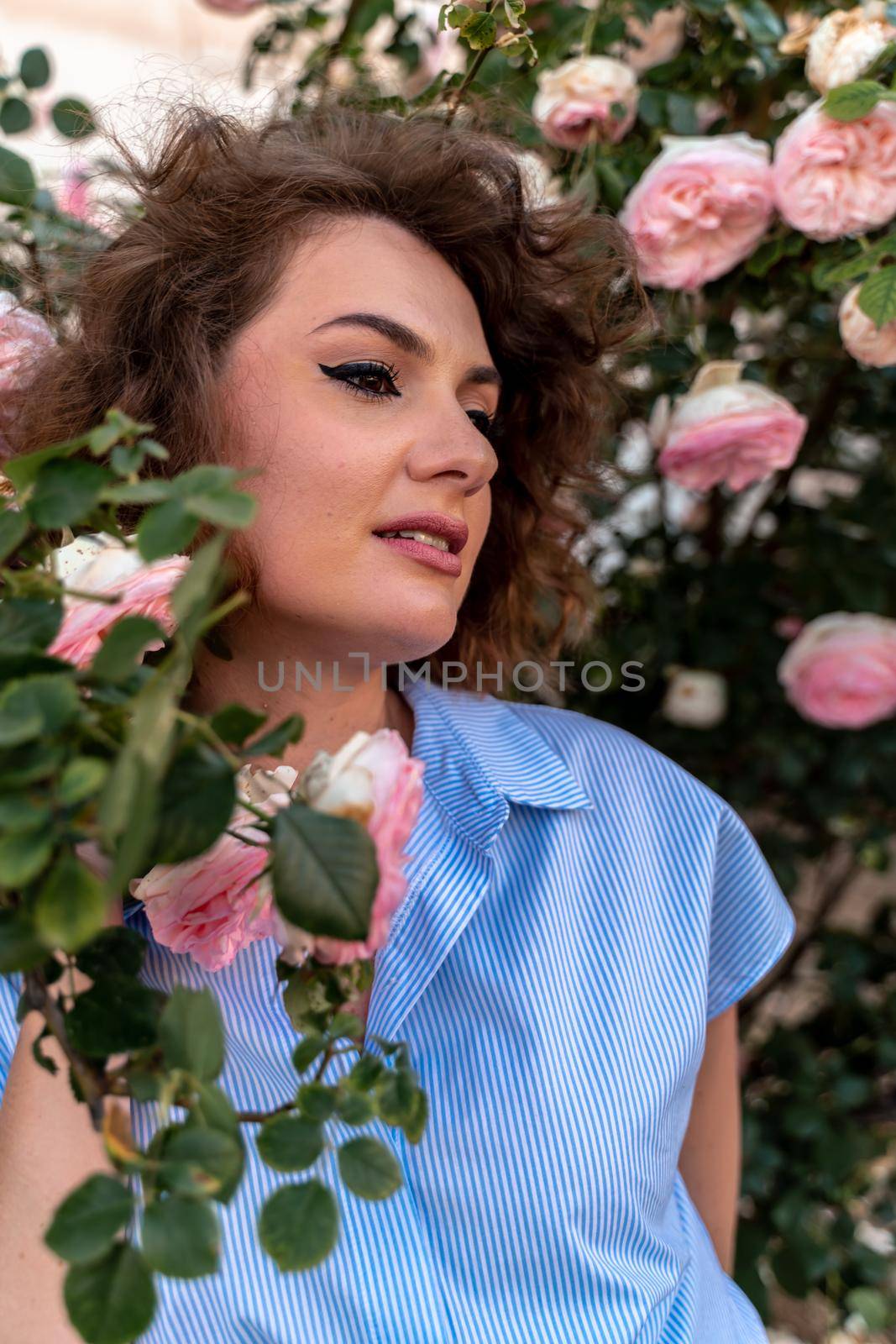 Portrait of a young woman in spring. Flowers of pink roses bloom