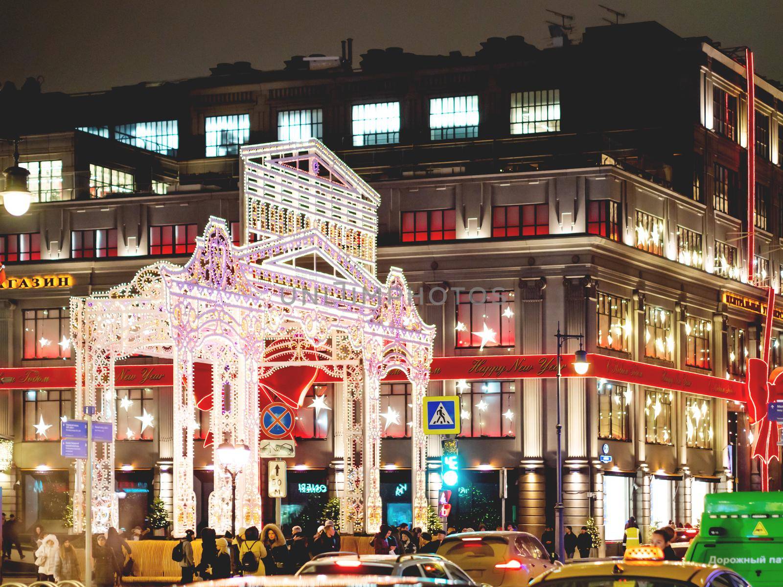 TSUM store facade decorated for New Year and Christmas celebration. Crowd of people near holiday gates decorated with light bulbs. by aksenovko