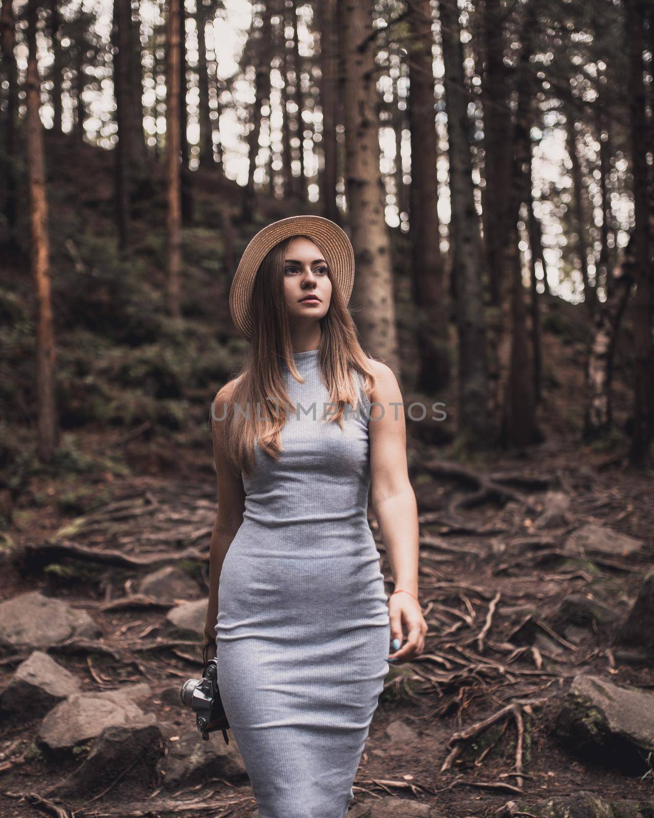 Slavic tanned fair-haired young girl with a boater hat on nature. Traveler tourist in a dark forest. constant tone of clothes. dark brown background