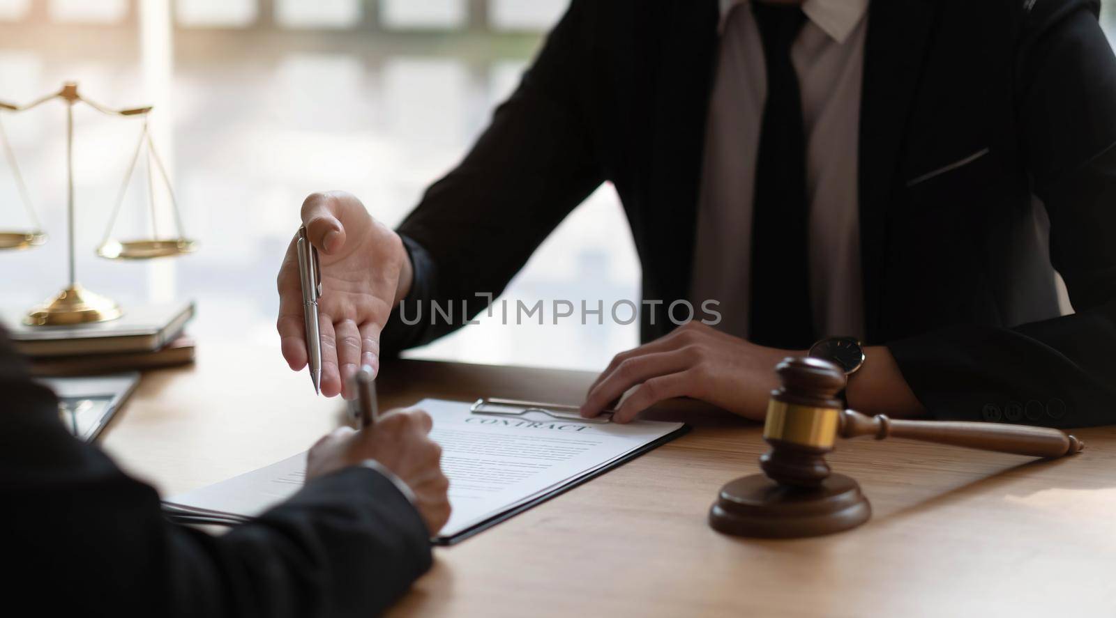 Business woman and lawyers discussing contract papers with brass scale on wooden desk in office. Law, legal services, advice, Justice concept. by wichayada