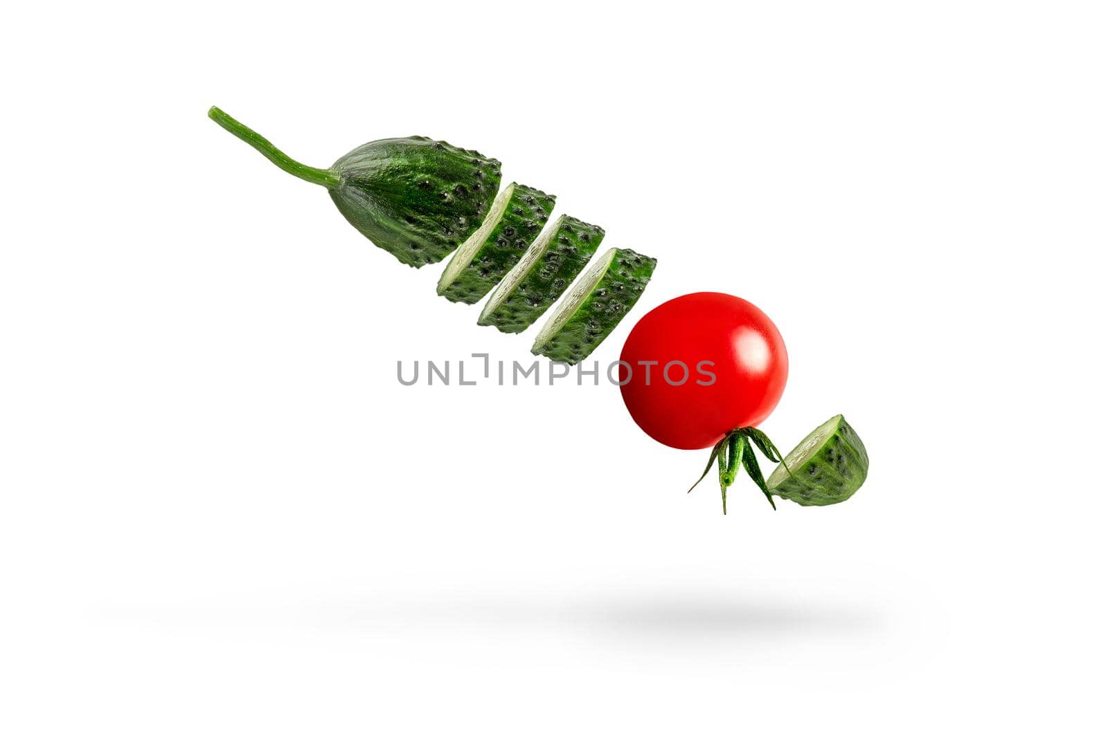 Isolated vegetables. Ingredients for salad. Mixed slices of cucumber and tomato in the air isolated on white background. by SERSOL