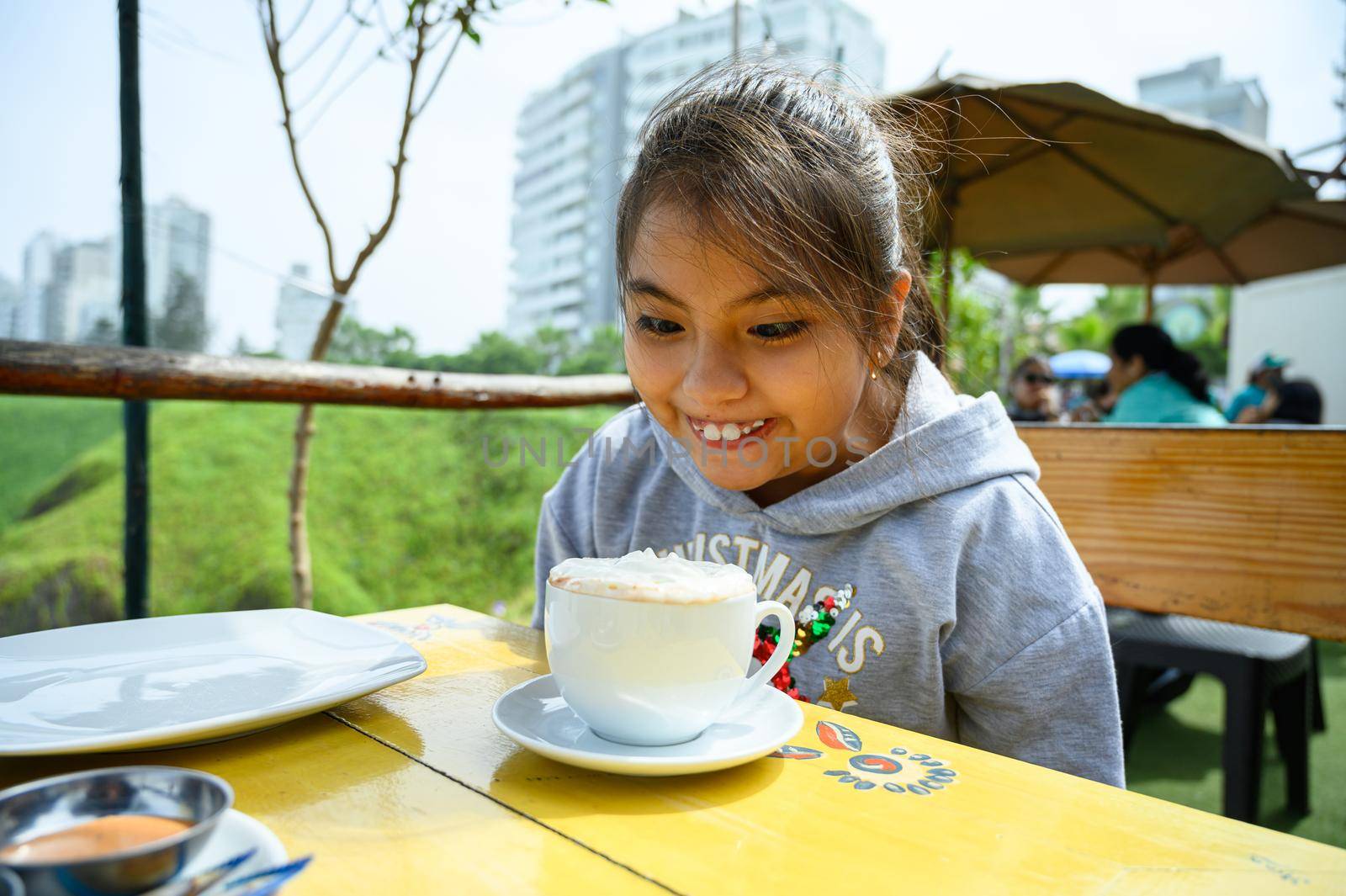 Beautiful girl sitting in the coffee shop with a cup of hot chocolate with whipped cream looking at him happily