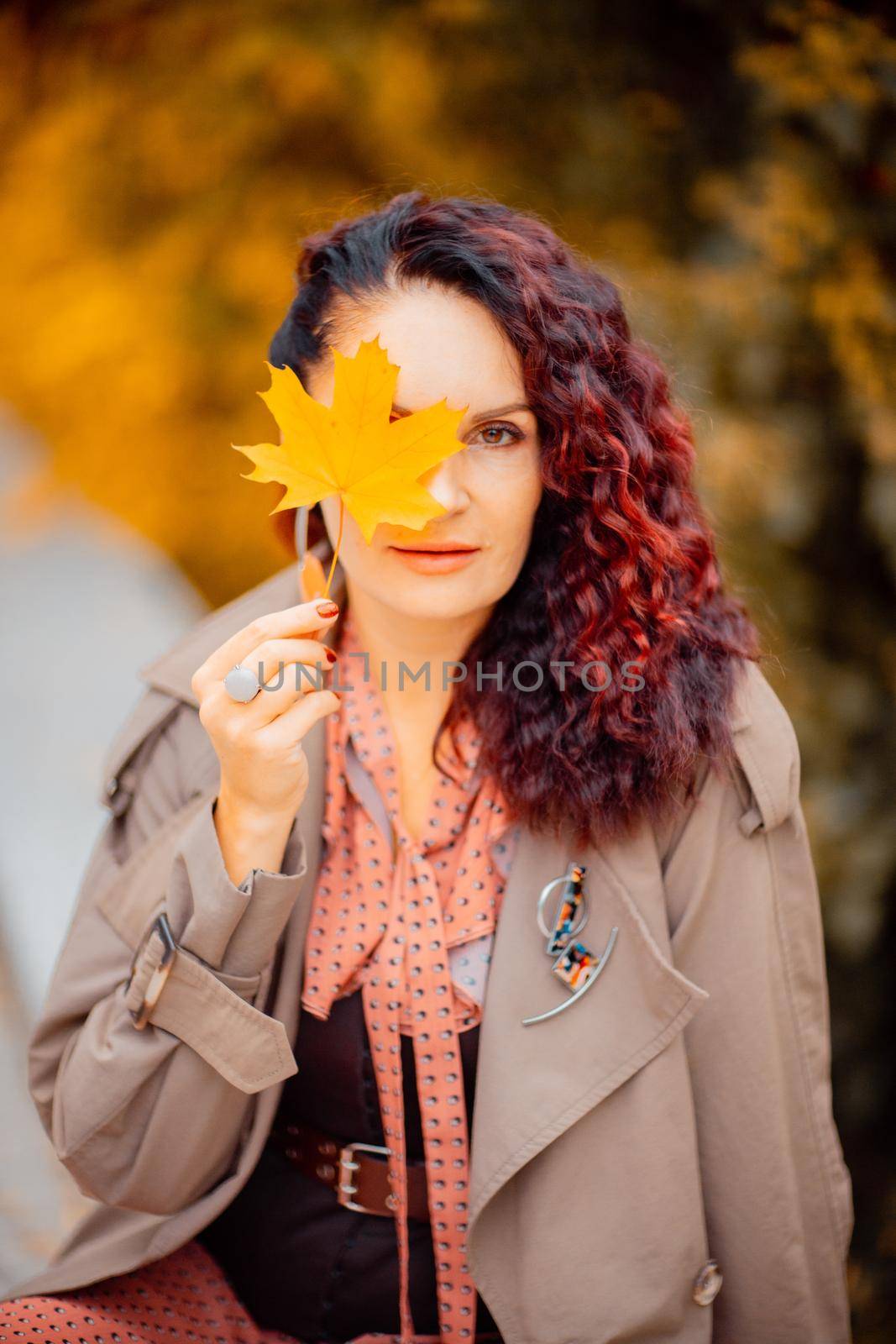 Beautiful girl walking outdoors in autumn. Smiling girl collects yellow leaves in autumn. Young woman enjoying autumn weather. by Matiunina