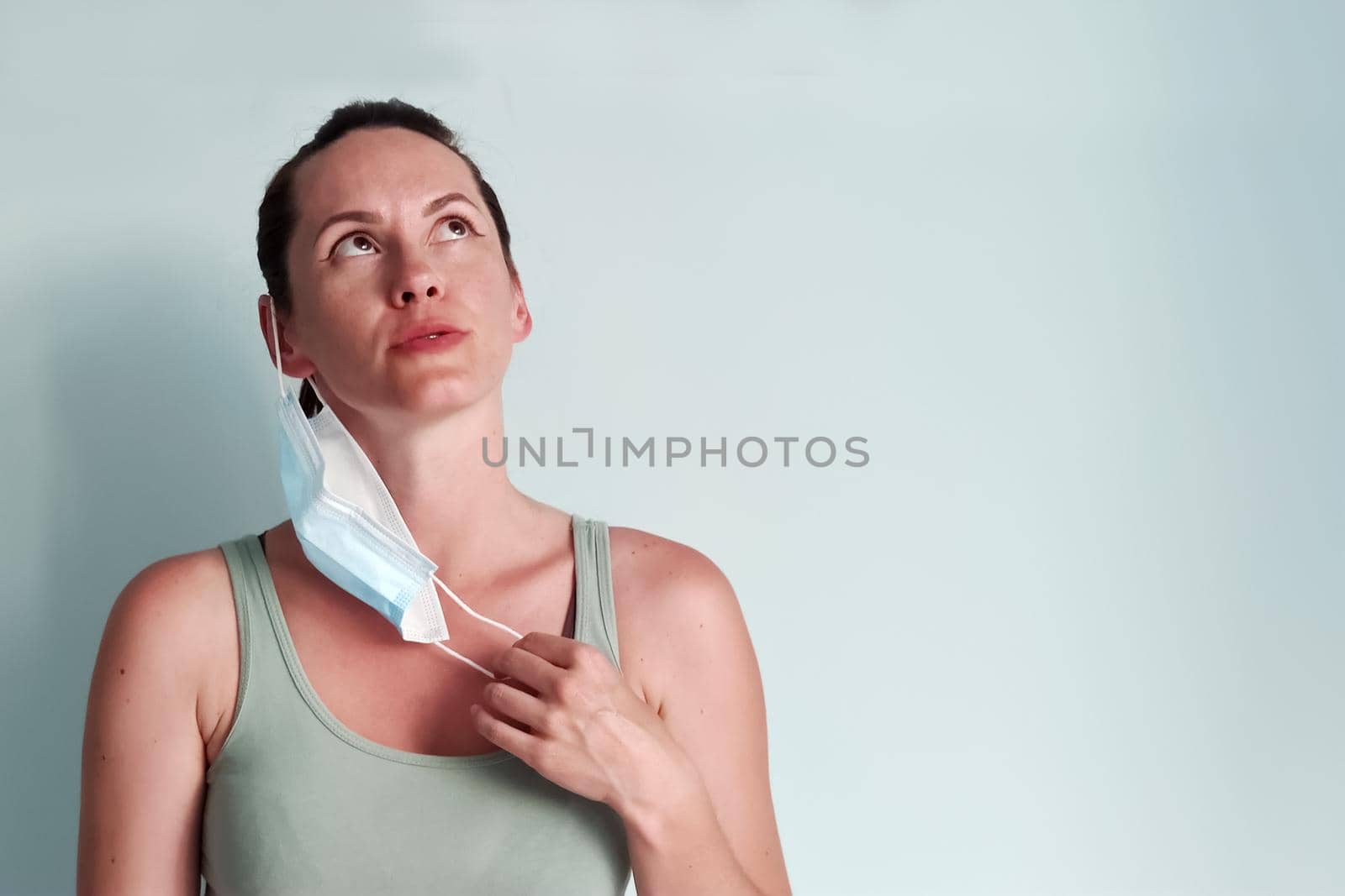 A young woman takes off her medical mask breathing in the air with relief. A place for copispace