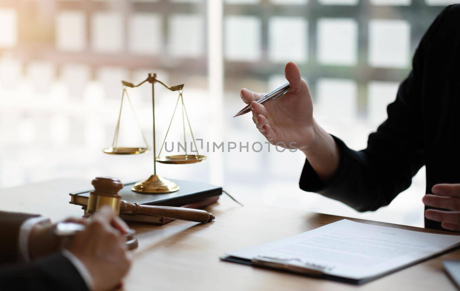 Business woman and lawyers discussing contract papers with brass scale on wooden desk in office. Law, legal services, advice, Justice concept. by wichayada