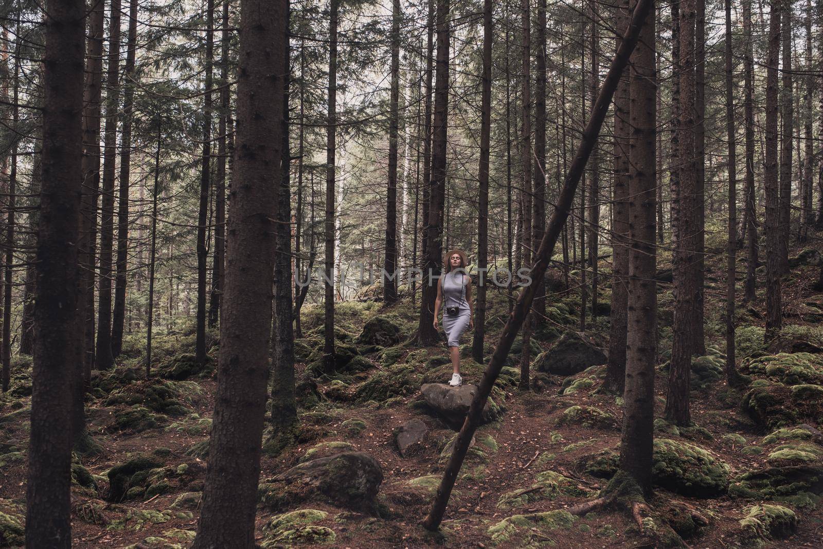 Slavic tanned fair-haired young girl with a boater hat on nature. Traveler tourist in a dark forest. constant tone of clothes. dark brown background