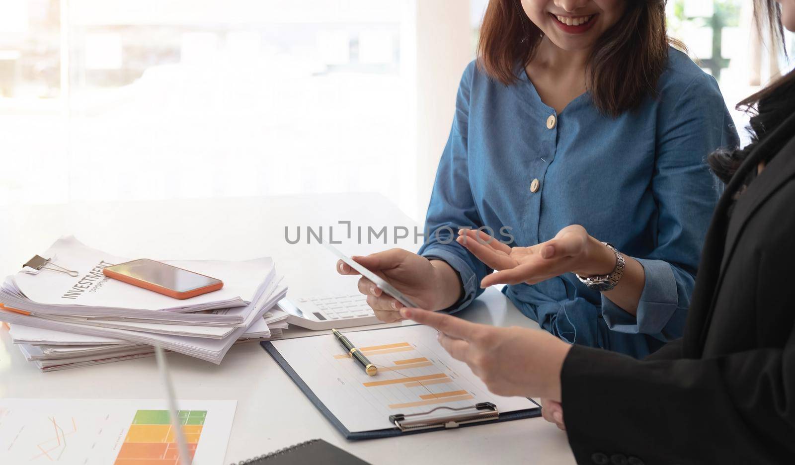 Two beautiful business people working together using a tablet at a modern office. by wichayada