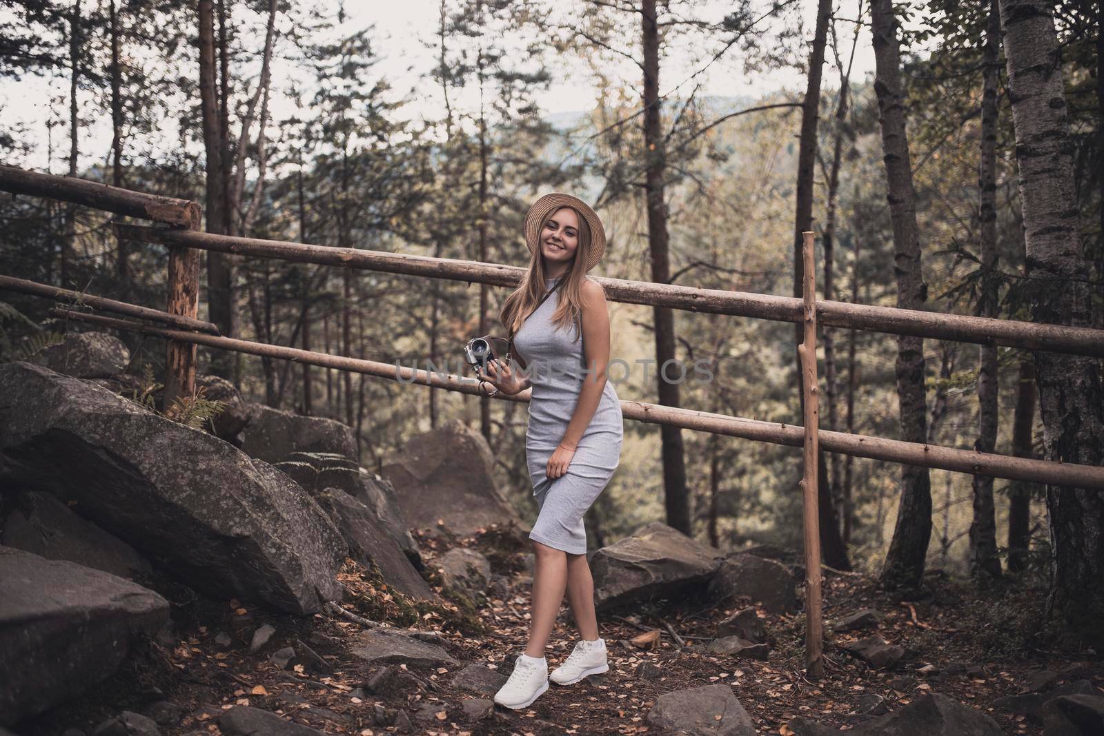 Slavic tanned fair-haired young girl with a boater hat on nature. Traveler tourist in a dark forest. constant tone of clothes. dark brown background