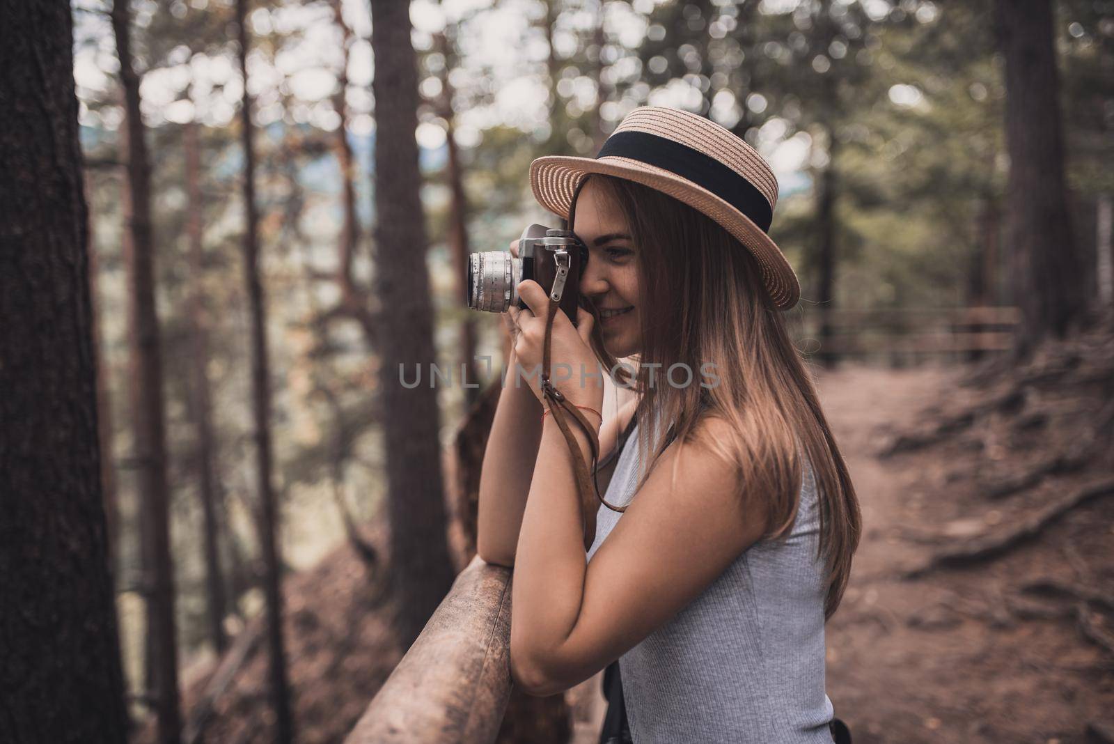 Slavic tanned fair-haired young girl with a boater hat on nature. Traveler tourist in a dark forest. constant tone of clothes. dark brown background