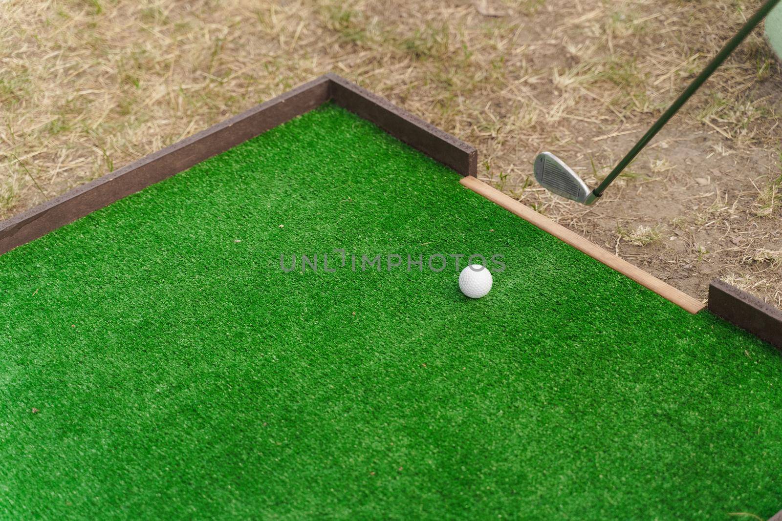 Golf sport game with niblick and white ball on the green grass. Playing in mini-golf. Empty place for advert right side by Rabizo