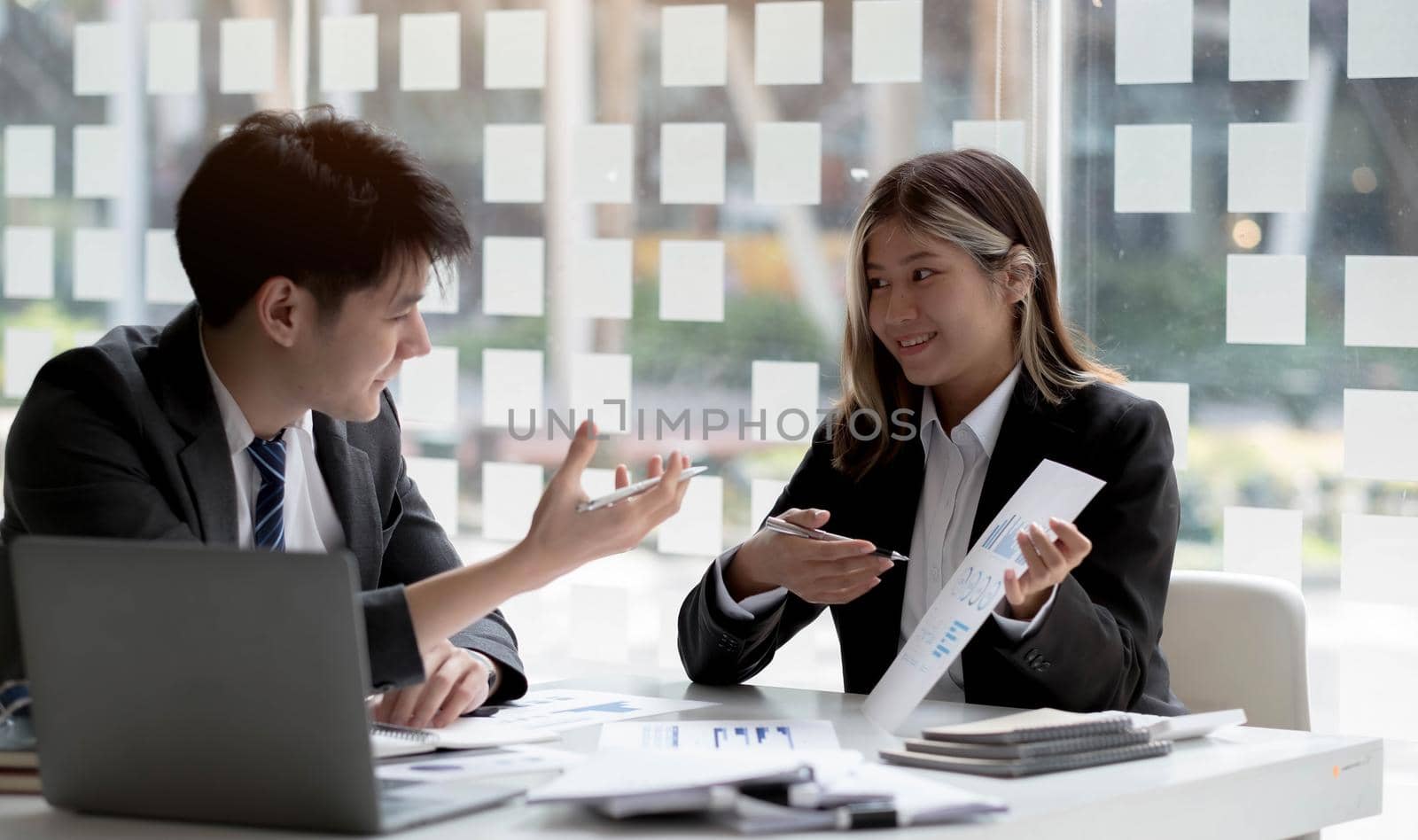 Two asian business woman and businessman work together to get the job done at the office..