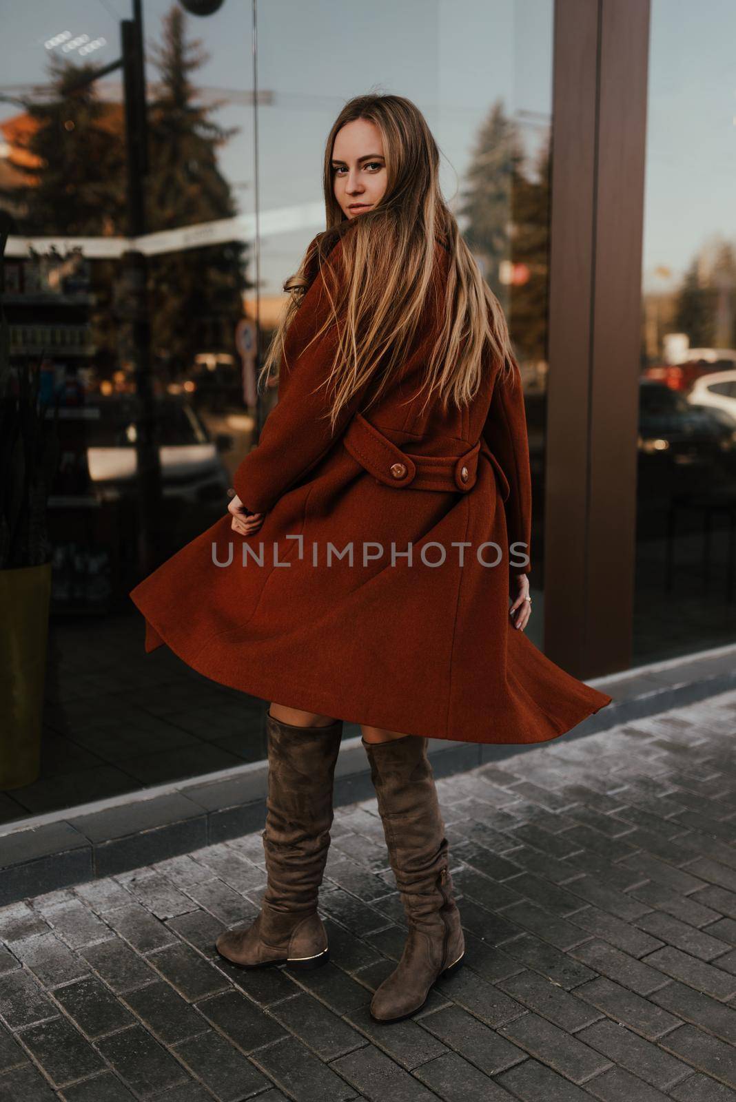 woman in autumn clothes walks on street background shop windows by AndriiDrachuk