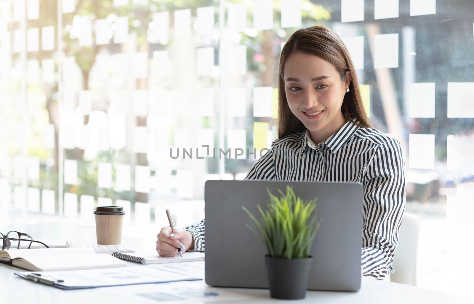 Charming asian businesswoman sitting working on laptop in office..