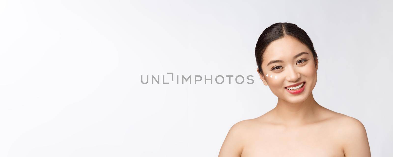 Skin care beauty woman. Beauty woman smiling applying cream. Beauty portrait of beautiful Asian Caucasian female model isolated on white. by Benzoix