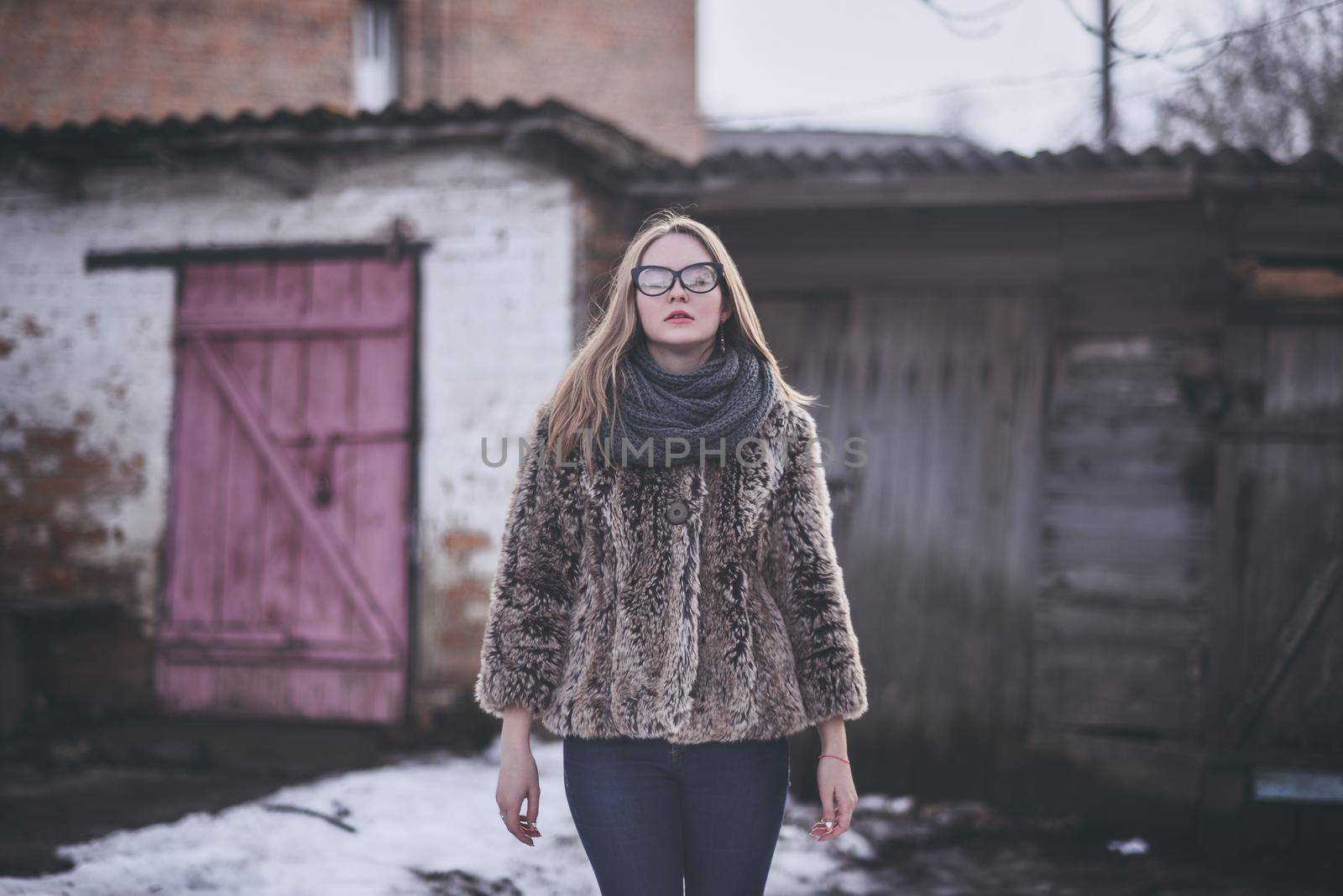 Girl blonde in cat eyes glasses in an artificial faux fur coat in winter by AndriiDrachuk