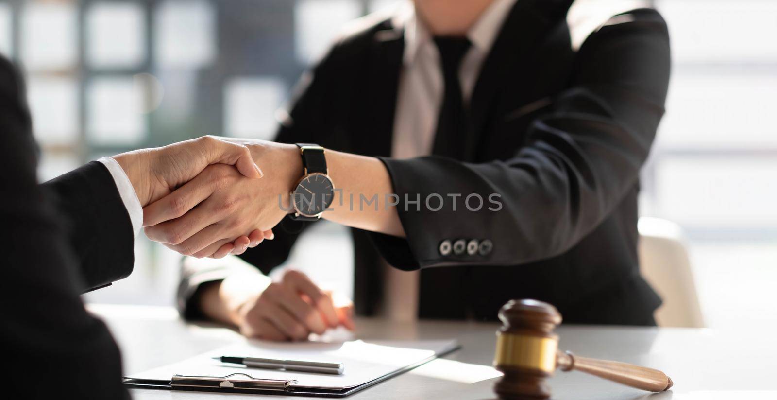 Businessman shaking hands to seal a deal with his partner lawyers or attorneys discussing a contract agreement. by wichayada