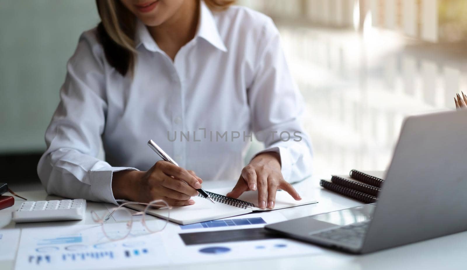 Pretty and charming asian businesswoman sitting happily smiling with laptop computer in the office. by wichayada