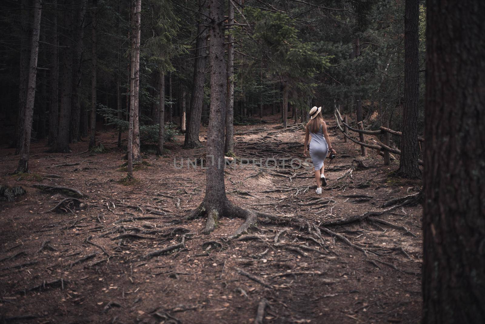 Slavic tanned fair-haired young girl with a boater hat on nature. Traveler tourist in a dark forest. constant tone of clothes. dark brown background