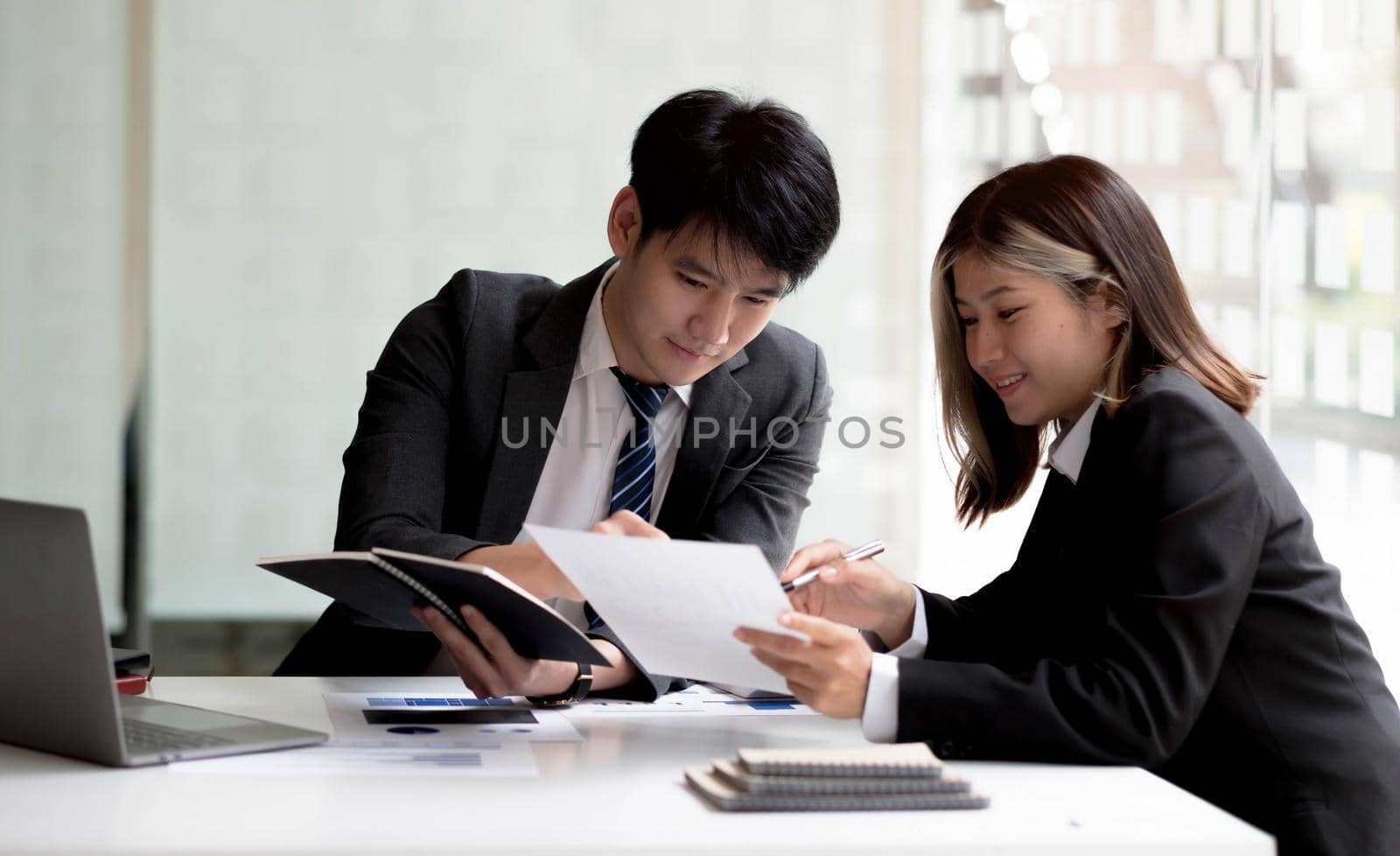 Two asian business woman and businessman work together to get the job done at the office. by wichayada