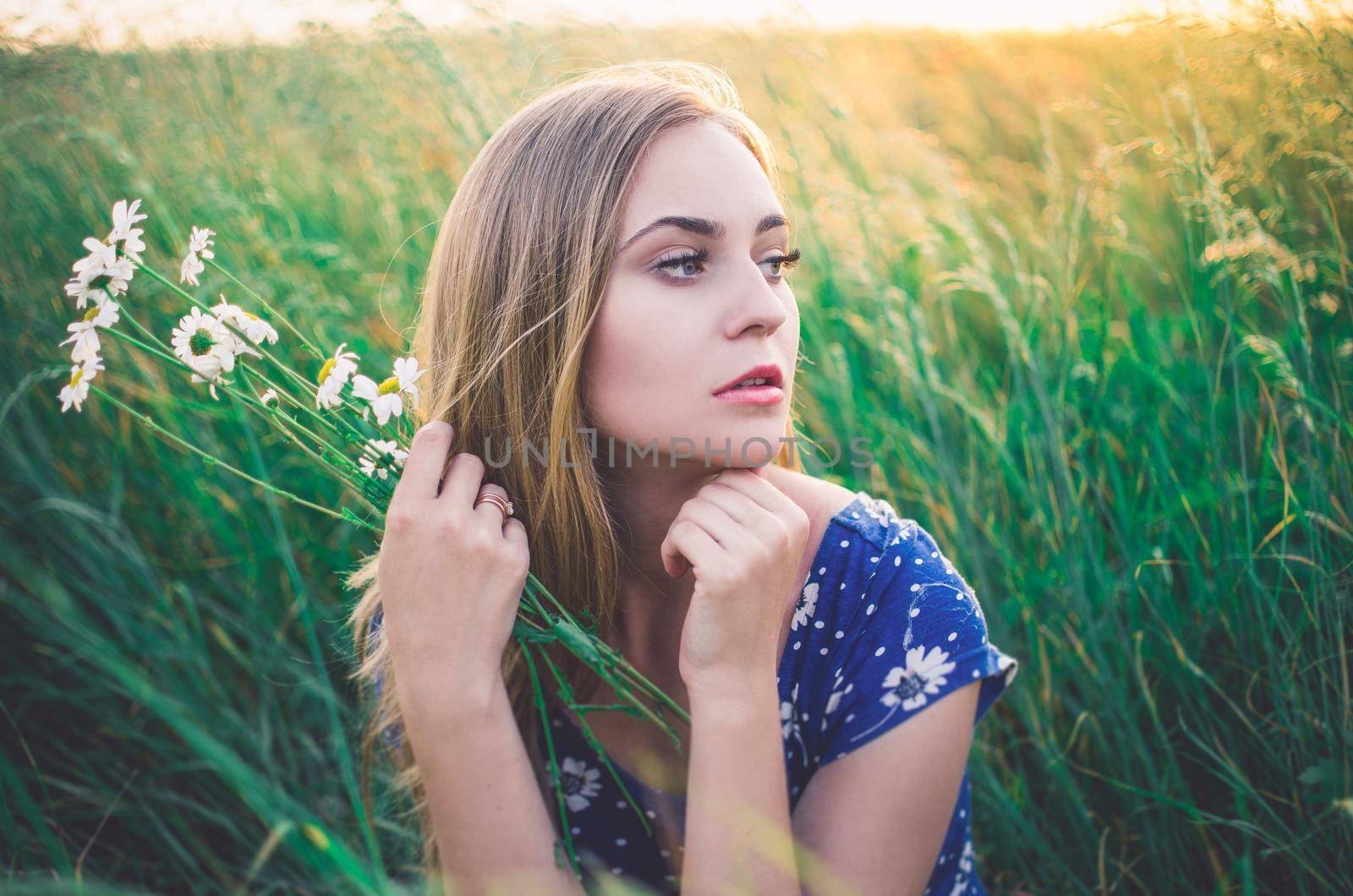 Girl sit in tall grass. A bouquet daisies in hand. by AndriiDrachuk