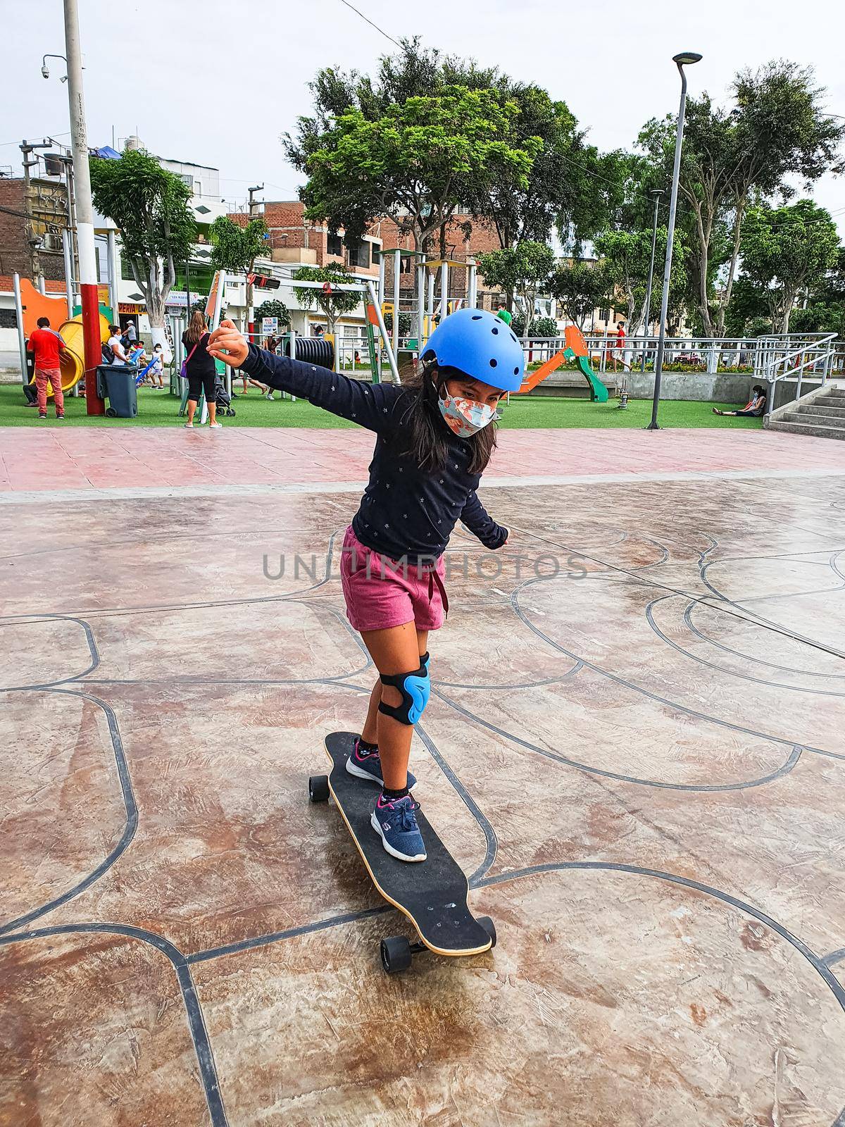 Beautiful skater girl with her protection helmet riding her longboard in the city