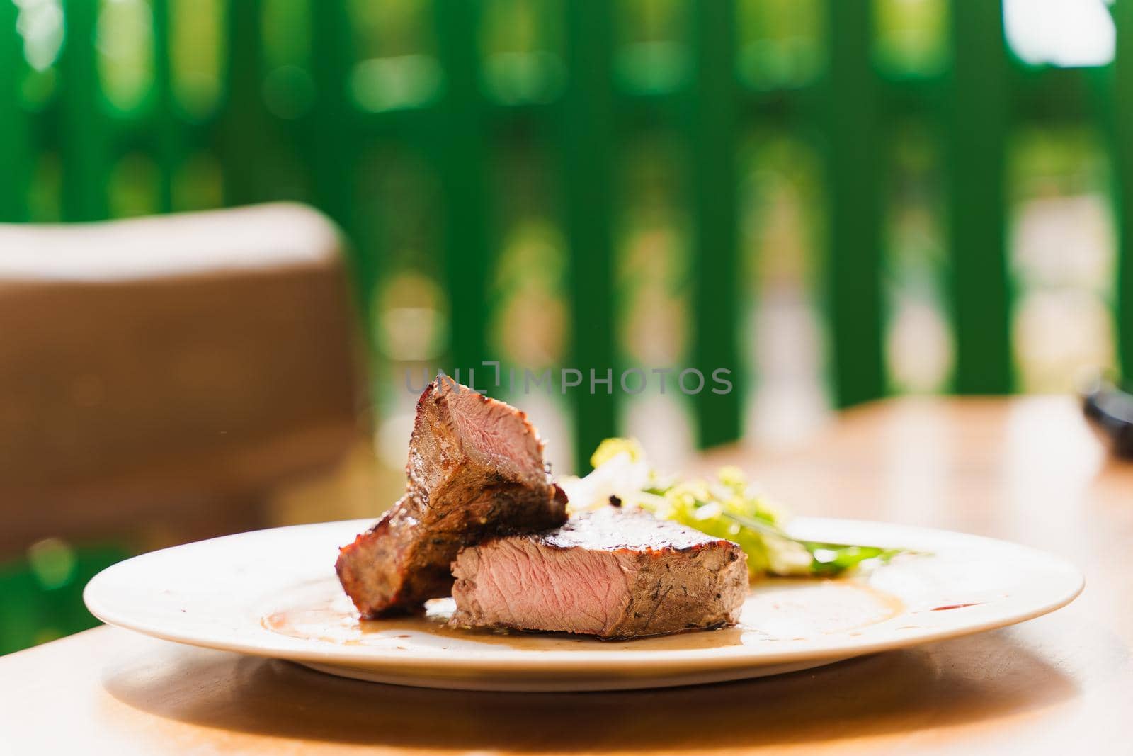 Steak on white plate on the background of the restaurant. Medium-rare juicy meat.