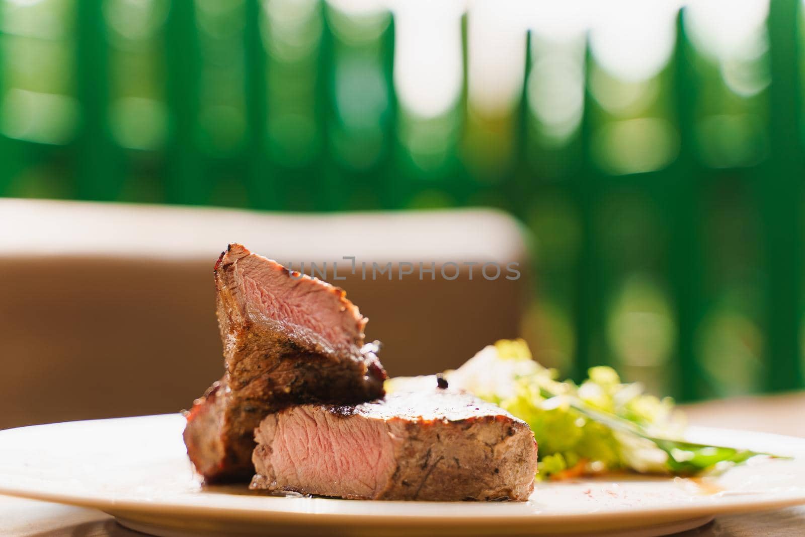 Steak on white plate on the background of the restaurant. Medium-rare juicy meat.