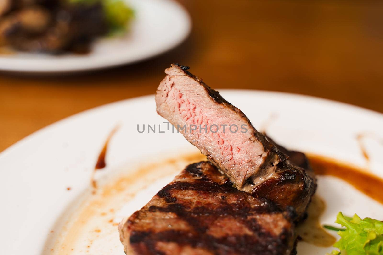 Steak on white plate on the on wooden table. Medium-rare juicy meat.