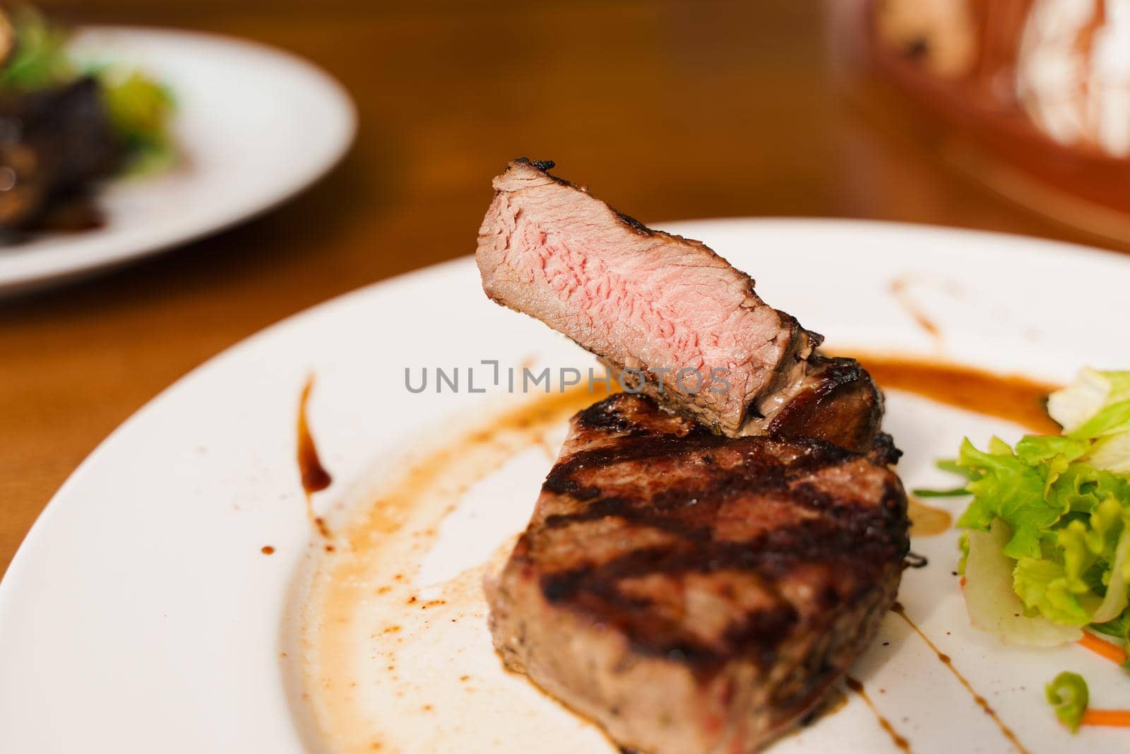 Steak on white plate on the on wooden table. Medium-rare juicy meat.