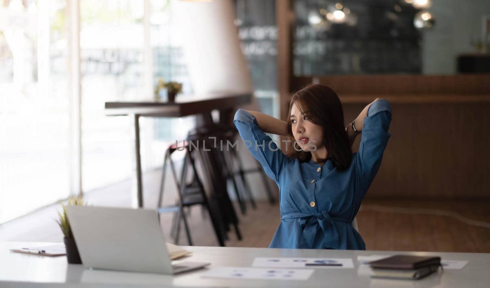 Asian woman enjoy and happy of relaxing at the office. Hold hands behind head concept of success future..
