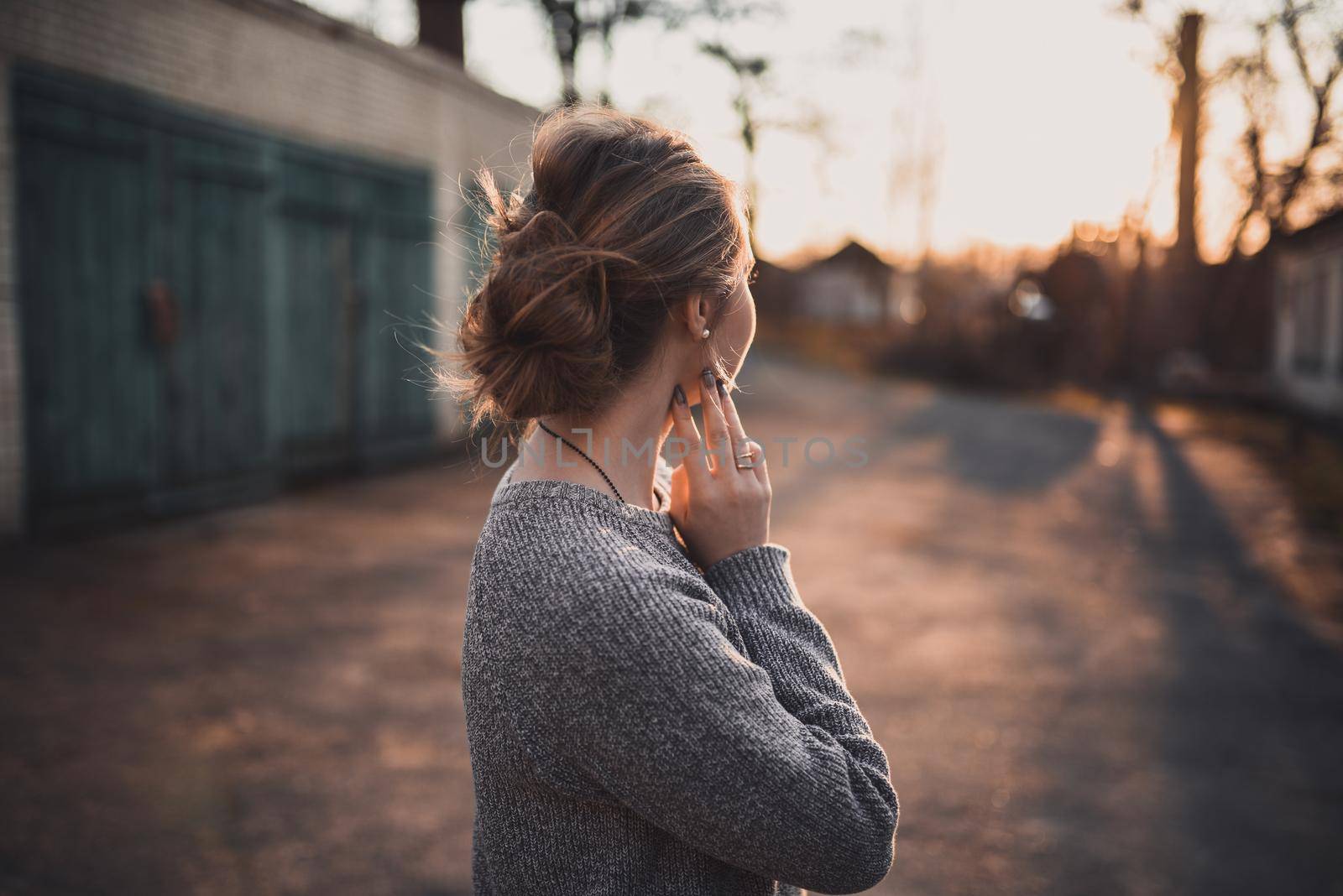 beautiful young blonde model girl smile. gray knitted sweater. On the Sunset. Portrait. hair tied in a bun