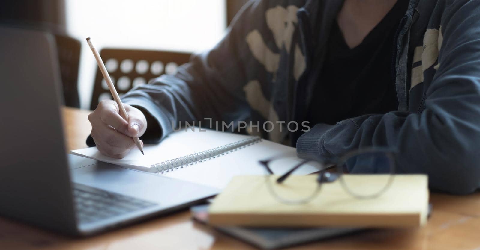 Close up women using laptop and note some data on notepad.