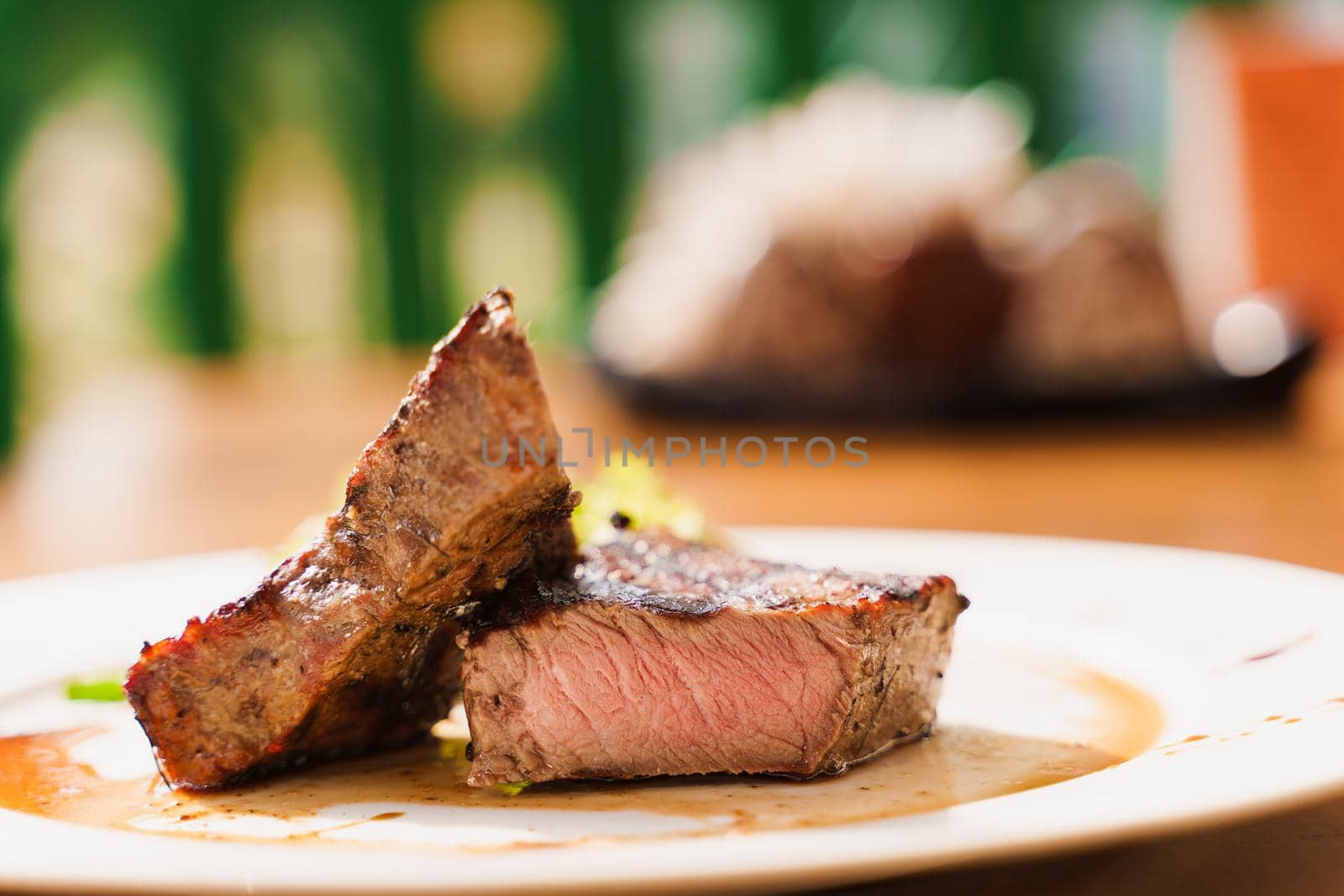 Steak on white plate on the background of the restaurant. Medium-rare juicy meat.