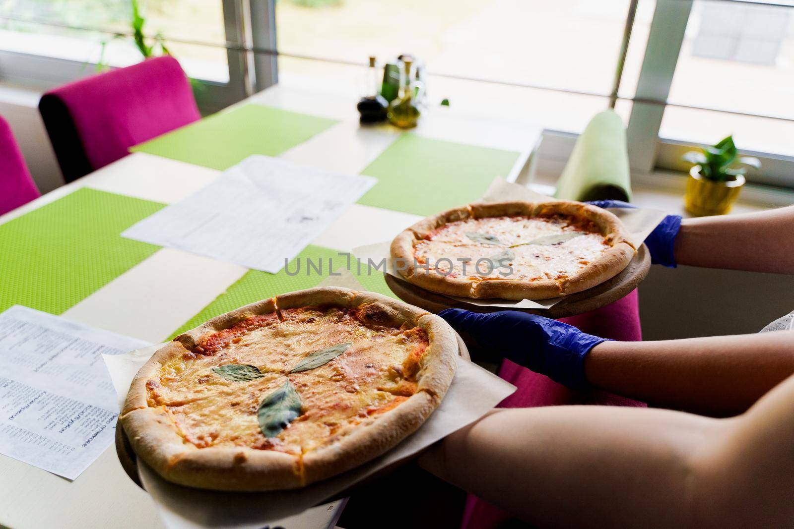 Pizza with tomatoes, mozzarella cheese, basil. Waiter with gloves takes out margarita pizza by Rabizo