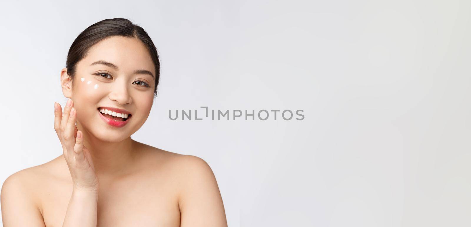 Skin care beauty woman. Beauty woman smiling applying cream. Beauty portrait of beautiful Asian Caucasian female model isolated on white
