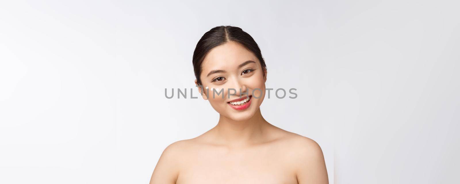 Skin care beauty woman. Beauty woman smiling applying cream. Beauty portrait of beautiful Asian Caucasian female model isolated on white. by Benzoix