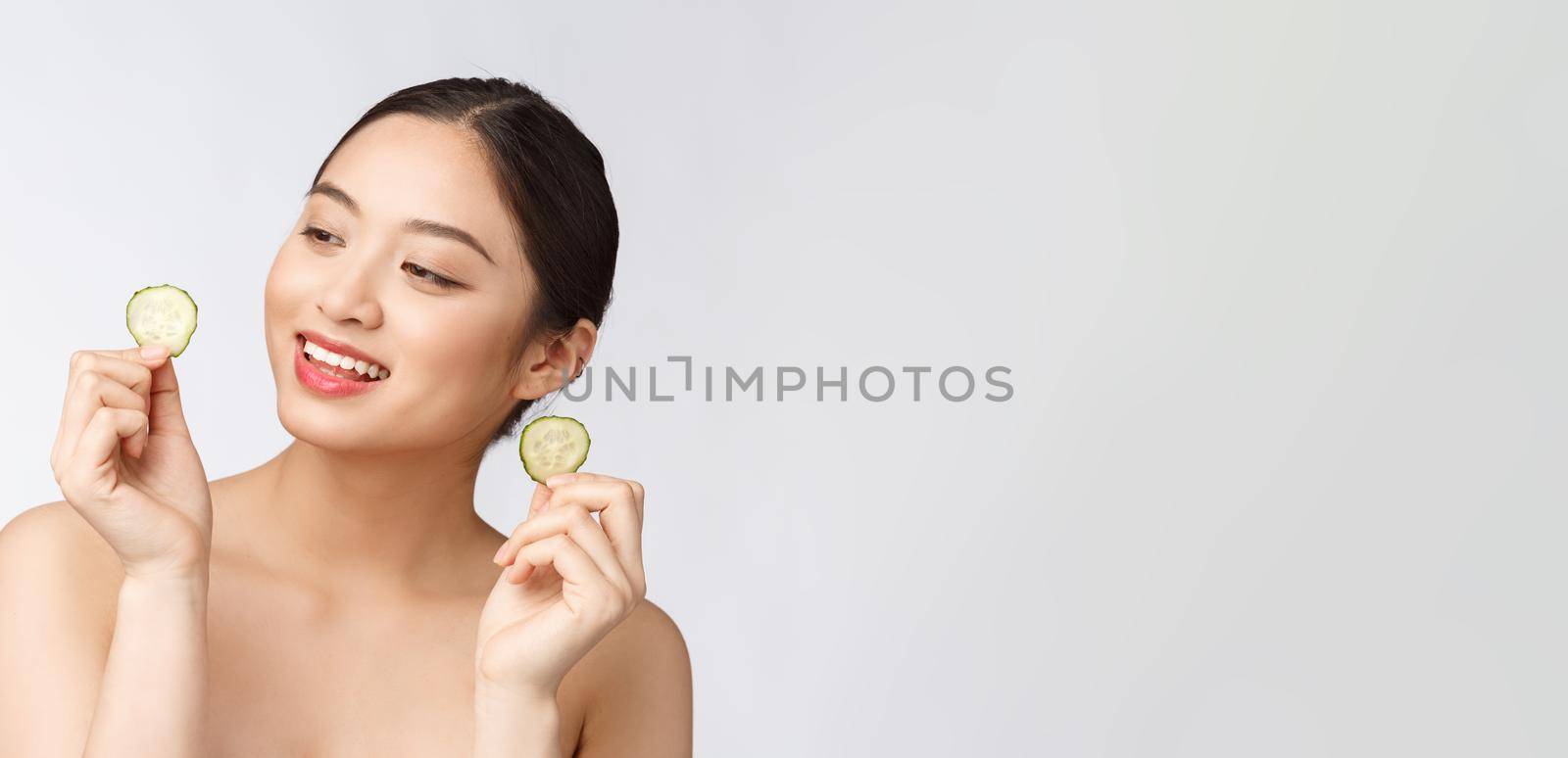 Natural homemade fresh cucumber facial eye pads facial masks. Asian woman holding cucumber pads and smile relax with natural homemade by Benzoix