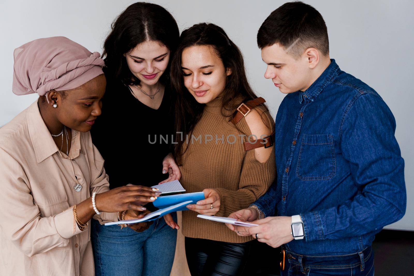 Multiethnic students and teacher study foreign languages together in class. Studing with notebook. Black attractive girl student study with white people together and look into camera. by Rabizo