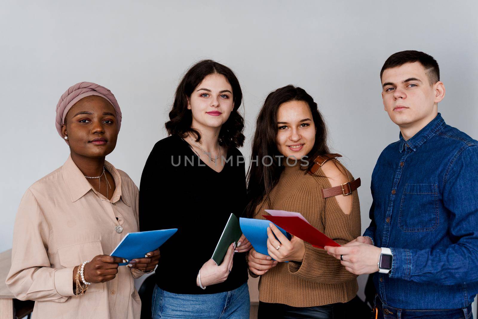 Multiethnic students and teacher study foreign languages together in class. Studing with notebook. Black attractive girl student study with white people together and look into camera