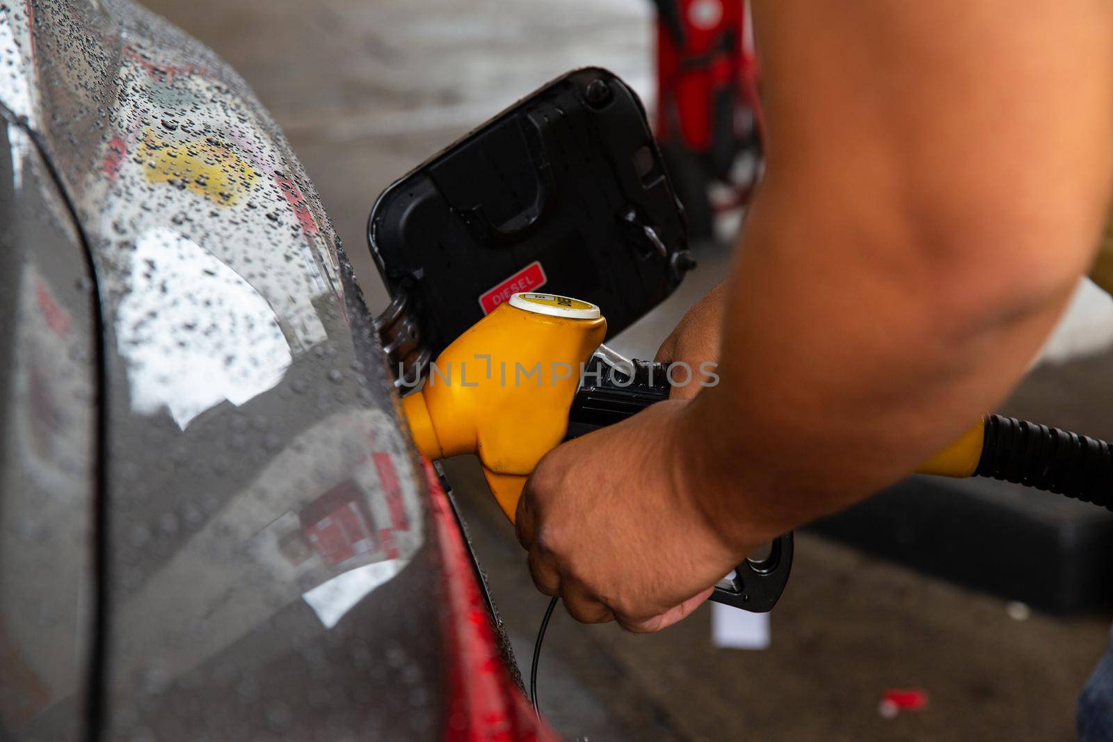 Man filling gasoline fuel in car holding pump. Closeup on male hand refuel car. The concept of increasing fuel prices.