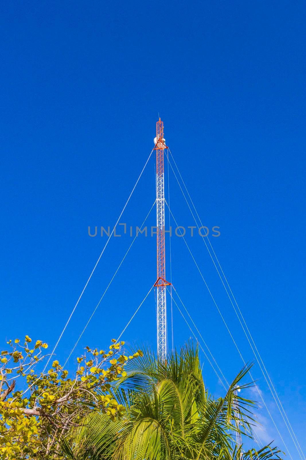 Red white 5G tower with blue sky background radiation kills us in Tulum in Mexico.