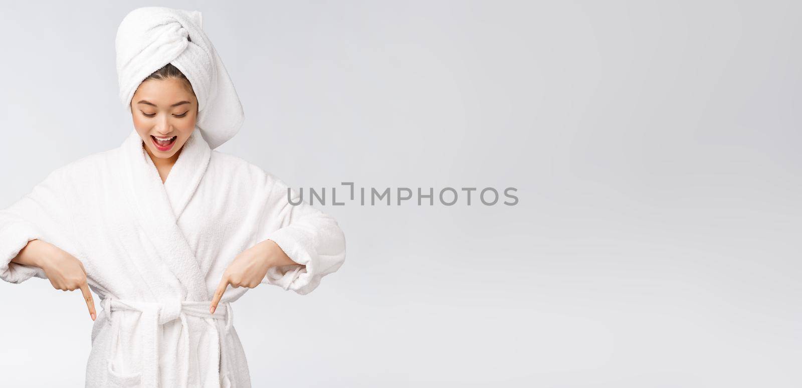 Beauty portrait of young woman showing and pointing finger to empty copy space, asian beauty in bathrobe