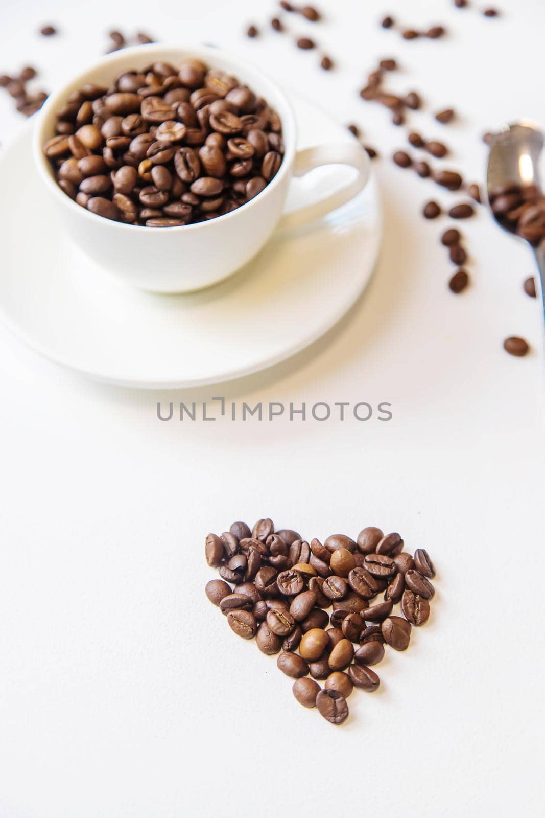 white cup and coffee beans on a white background. Selective focus.