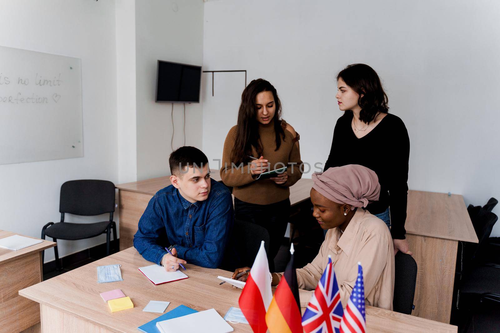 English class study with students from diffent countries: Poland, Germany, USA. Teamwork. Working in multiethnic students. Teacher study foreign languages together in class. Studing with laptop.