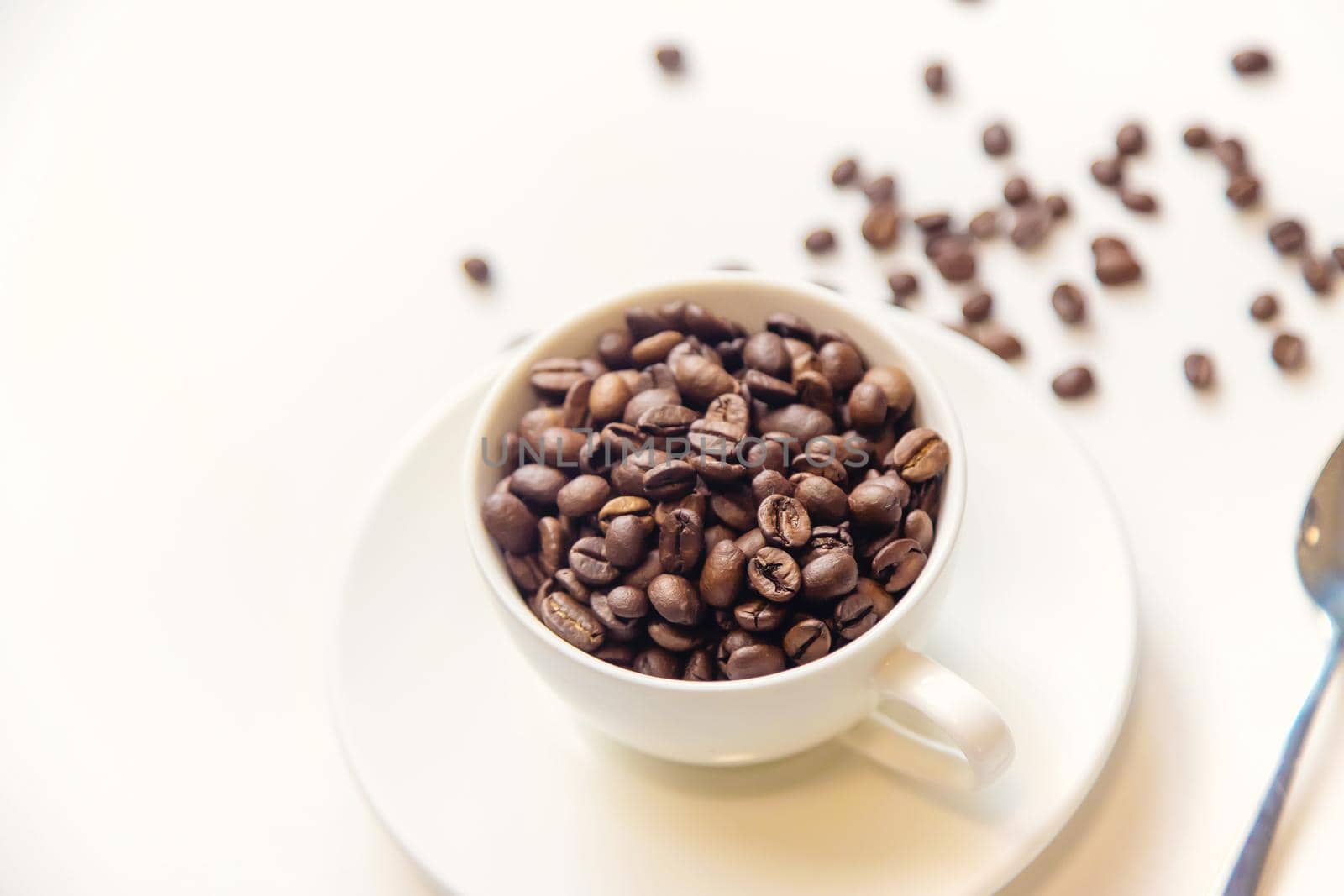 white cup and coffee beans on a white background. Selective focus.