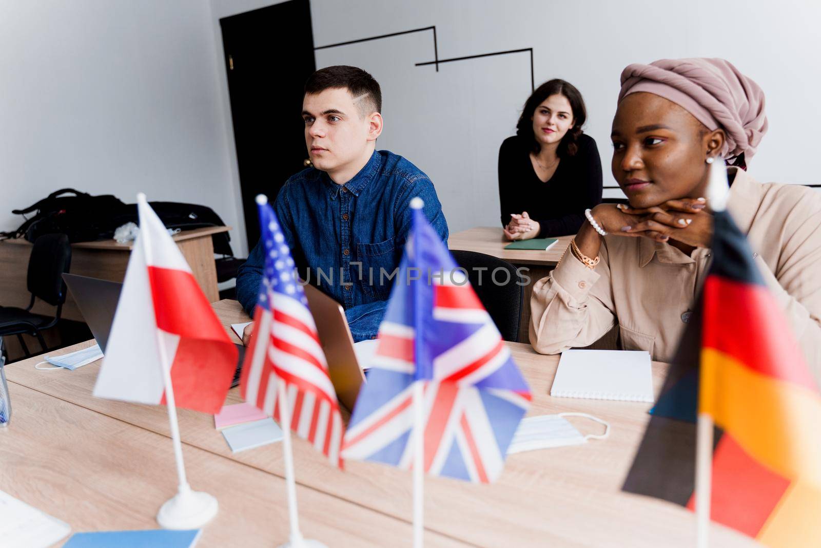 Foreign school private study with a school girl. Teacher explain grammar of native language using laptop. Prepearing to exam with tutor. English, British, German and Poland flags in front.